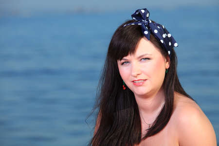 Picnic outdoors. Portrait of young woman with the sea in the background. Retro style.の写真素材