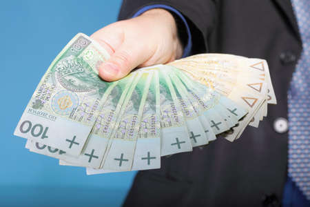 Businessman holding polish money banknote blue backgroundの写真素材