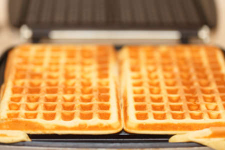 Waffle iron in the kitchen. Preparing homemade waffles.の写真素材