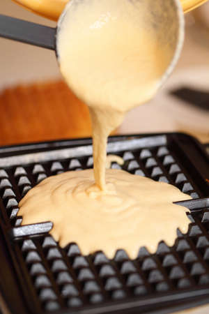 Waffle iron in the kitchen. Preparing homemade waffles, pouring a doughの写真素材