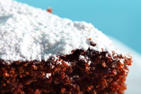 Close up chocolate cake with icing sugar blue backgroundの写真素材