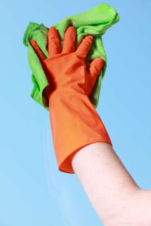 hand in orange glove cleaning window with green ragの写真素材