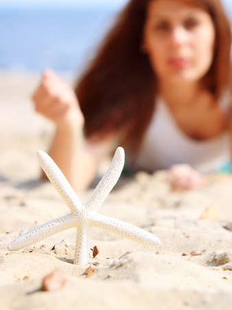 young woman on seacoast with starfish on sand  - summer vacationの写真素材