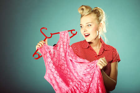 Retro style. Young happy woman shopping for dress, shopper girl choosing pink dress during sale.