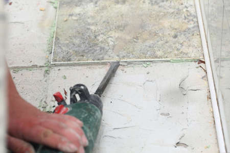 manual worker disassembling old floor tilesの写真素材