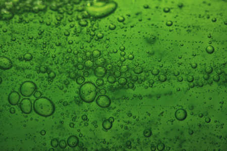 Green abstract blurred liquid background with soap bubblesの写真素材