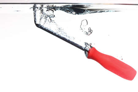 Red screwdriver tool in the water splash over white background