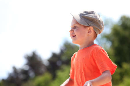 Portrait little boy kid in cap outdoor green backgroundの写真素材