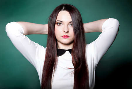 Young woman straight long dark hair make up posing in studio fashion photo green background