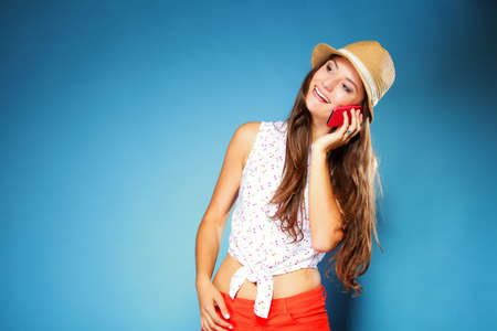 Happy smiling summer girl talking on mobile phone, blue background