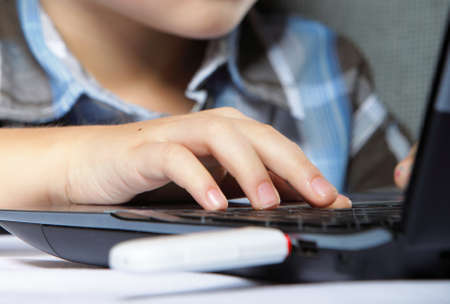 Cropped image of boy's schoolboy's hand typing on laptop keyboardの写真素材