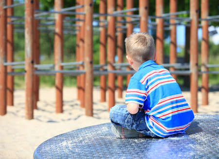 thoughtful child boy or kid in playground on leisure equipmentの写真素材
