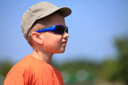 Little boy kid with sunglasses and cap outdoor sky background