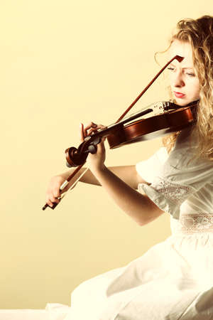 The blonde girl music lover on pier with a violin at sunset or sunrise.  Love of music concept.の写真素材