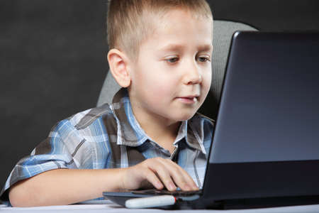 Computer addiction child boy with laptop notebook black backgroundの写真素材
