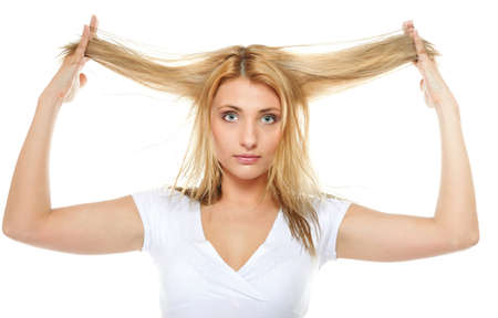 Damaged dry woman hair. Closeup portrait of woman holding hands long hair and looking unhappy. Isolated on white background.の写真素材