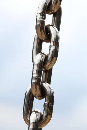 Chain Links closeup of a metal steel chain link segment from a children's swing set. Sky background.の写真素材