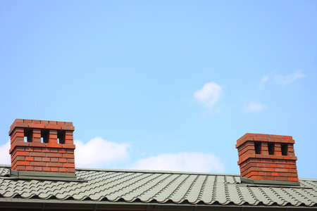 Red chimney on the roof blue sky backgroundの写真素材