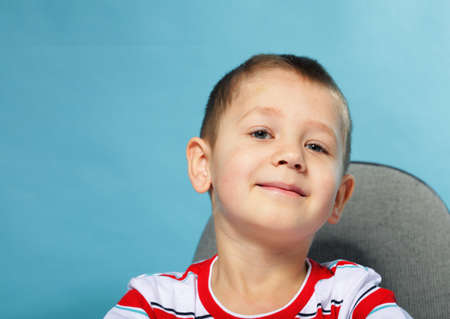 little smiling child boy schoolboy portrait on blue backgroundの写真素材