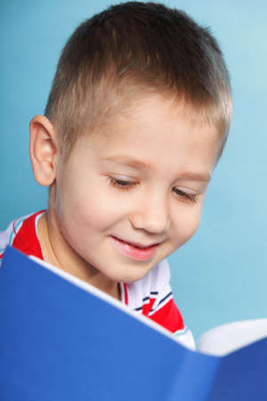 Young boy reading a book, child kid on blue background holding an open bookの写真素材