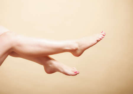 Beautiful perfect long woman girl legs barefoot body care pedicure on orangeの写真素材