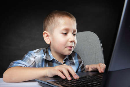Computer addiction child boy with laptop notebook black backgroundの写真素材