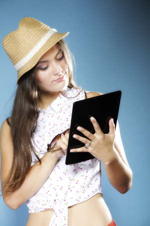 Internet modern lifestyle concept. Young summer girl in hat using tablet computer reading. Latin female with e-book reader touchpad pc.の写真素材