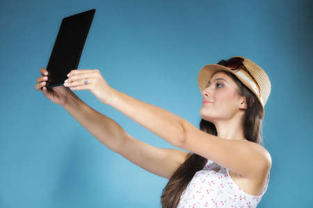 Internet modern lifestyle concept. Young summer girl in hat using tablet computer reading. Latin female with e-book reader touchpad pc.の写真素材