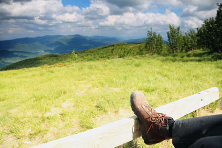 Hiking shoes boots. Male hiker enjoying view relaxing looking at nature in hills landscape...