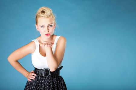 Retro style. Pin up blonde cute girl blowing a kiss on blue backgroundの写真素材