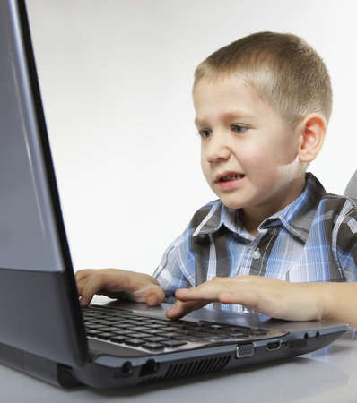 Computer addiction emotional child boy with laptop notebook playing games isolated on white...