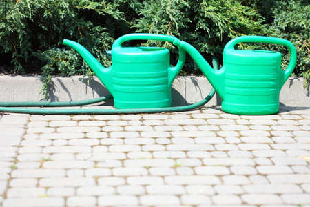 Gardening tools watering green can and hose in garden outdoorの写真素材