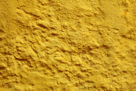 Close up yellow paint uneven old concrete wall background or textureの写真素材