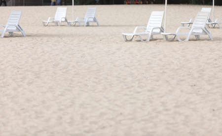 empty white pool plastic chairs deckchairs on sand beach. Vacation conceptの写真素材
