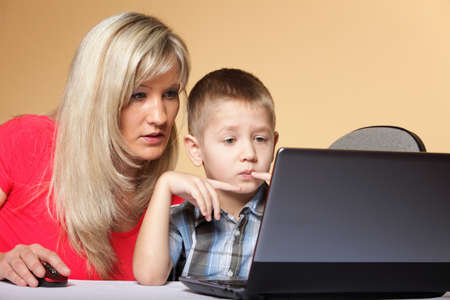 mother with son together looking on the laptop orange background