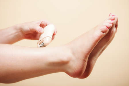woman shaving her legs with electric shaver depilation on orange. Beauty and skin body care concept.