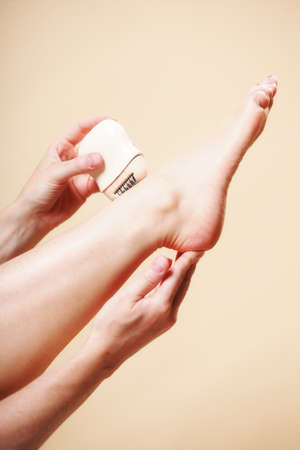 woman shaving her legs with electric shaver depilation on orange. Beauty and skin body care concept.の写真素材