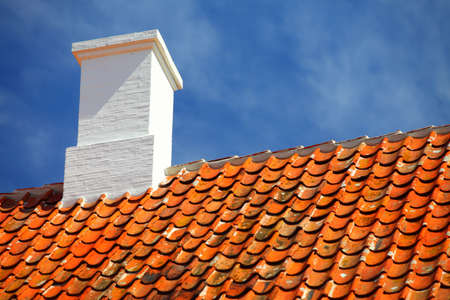 The old roofing tiles red clay house roof with chimney sky backgroundの写真素材