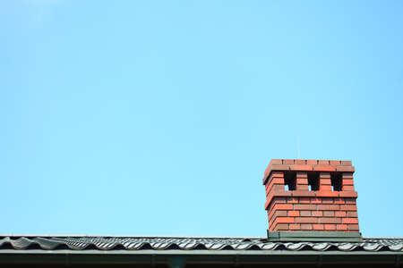 Red chimney on the roof blue sky backgroundの写真素材