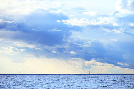 Gray deep blue fluffy thunder clouds stormy sky above a dark surface of the sea. Meteorology