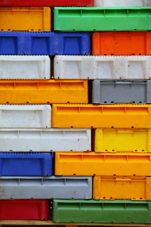 colorful boxes plastic crates background. Packing containers piles for fish storage of catch.の写真素材