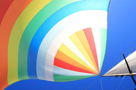The wind has filled the spinnaker on sailing yacht. Detail of a colorful sail against the deep blue sky.の写真素材