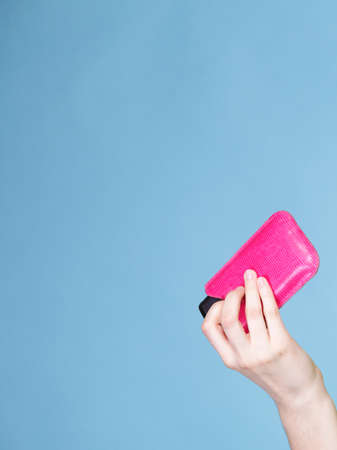 Female hand holding mobile phone in pink cover blue background with copy spaceの写真素材