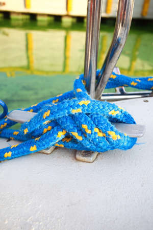 Sailboat yacht detailed parts, close up on metal cleat with blue line rope tied around it. Yachting.の写真素材