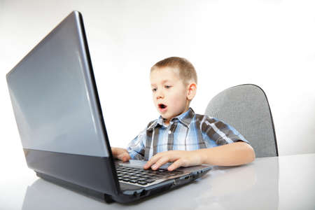 Computer addiction emotional child boy with laptop notebook playing games isolated on white backgroundの写真素材