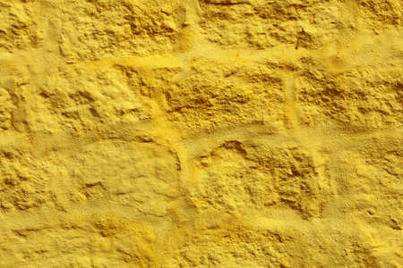 Close up yellow paint uneven old concrete wall background or textureの写真素材
