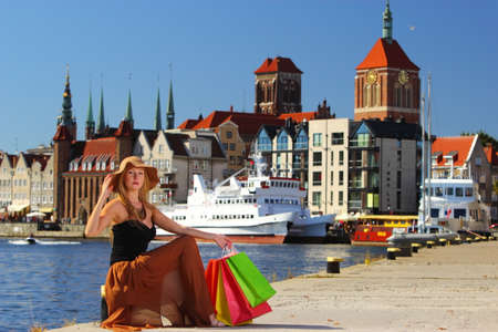 Stylish autumn shopper woman in hat with shopping sale bags in european city, old town Gdansk in the...