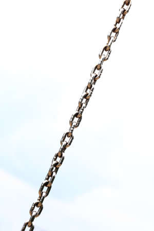 Chain Links closeup of a metal steel chain link segment from a children's swing set. Sky background.の写真素材
