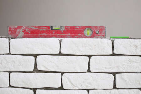 Red balance spirit building level in construction site. Check the level of a brick house wall