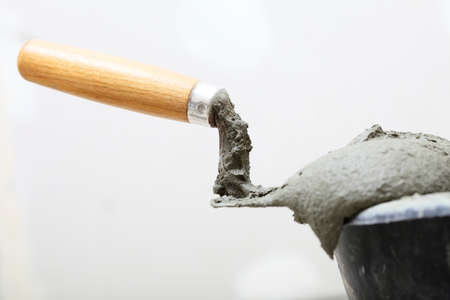 Renovation at home dirty trowel and bucket with mortar on construction building siteの写真素材